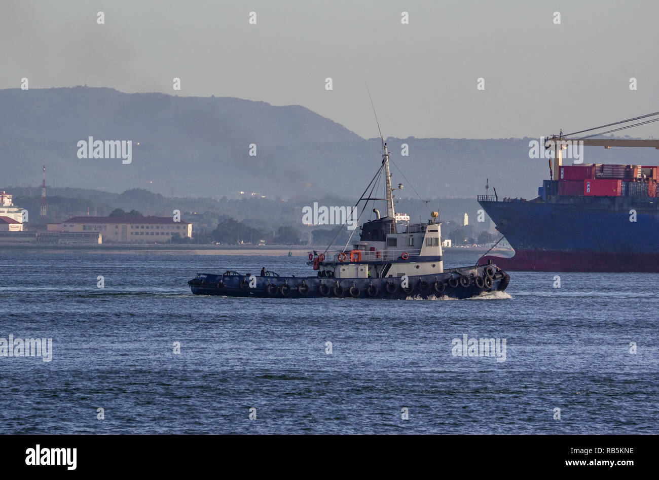 Lisbon - Portugal, tugboat assists a cargo ship on the Tagus River Stock Photo