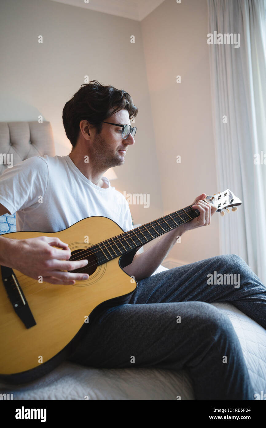 Man playing guitar in bedroom Stock Photo