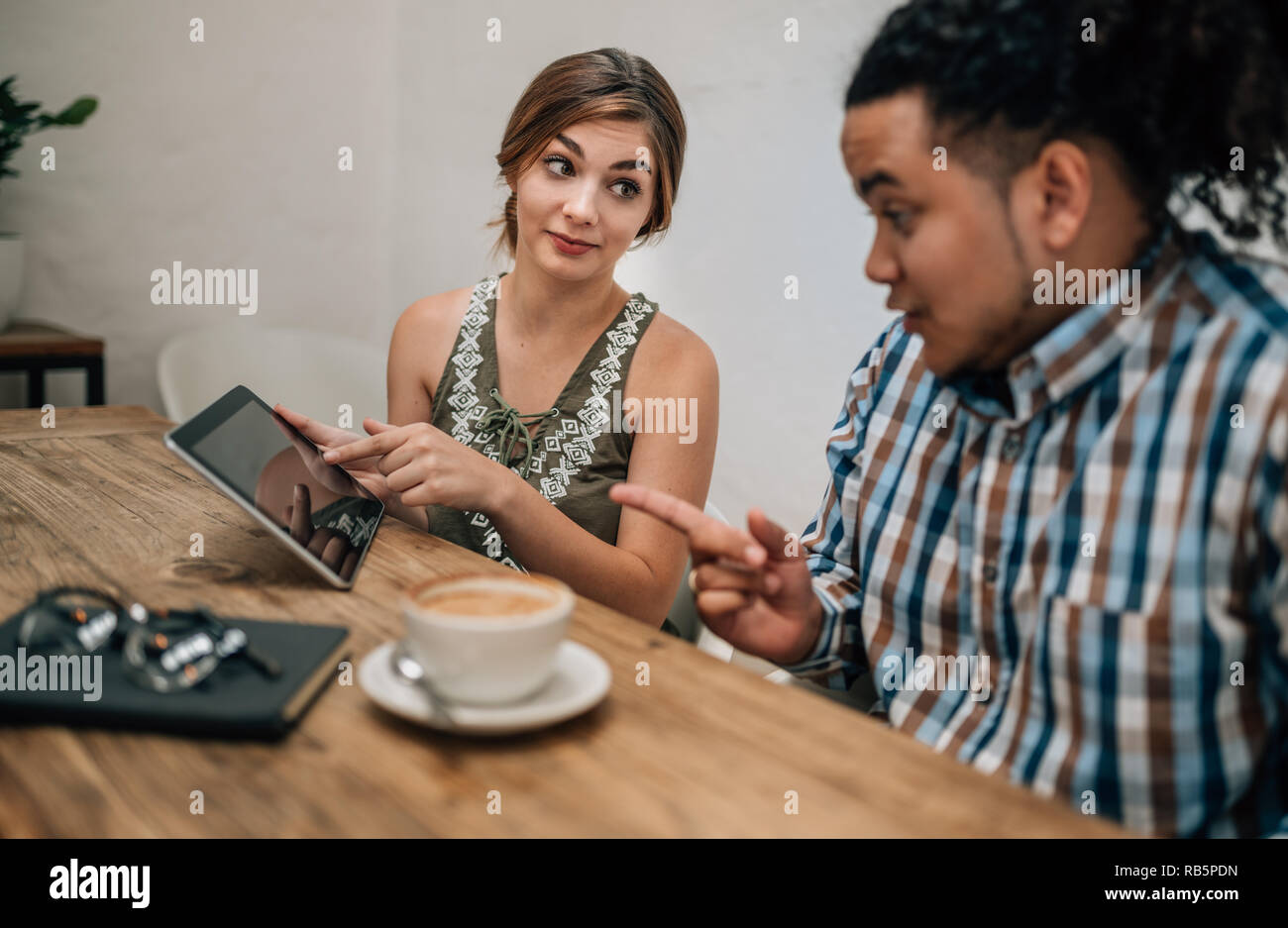 Two young creatives looking serious while pointing at a tablet ina boardroom Stock Photo