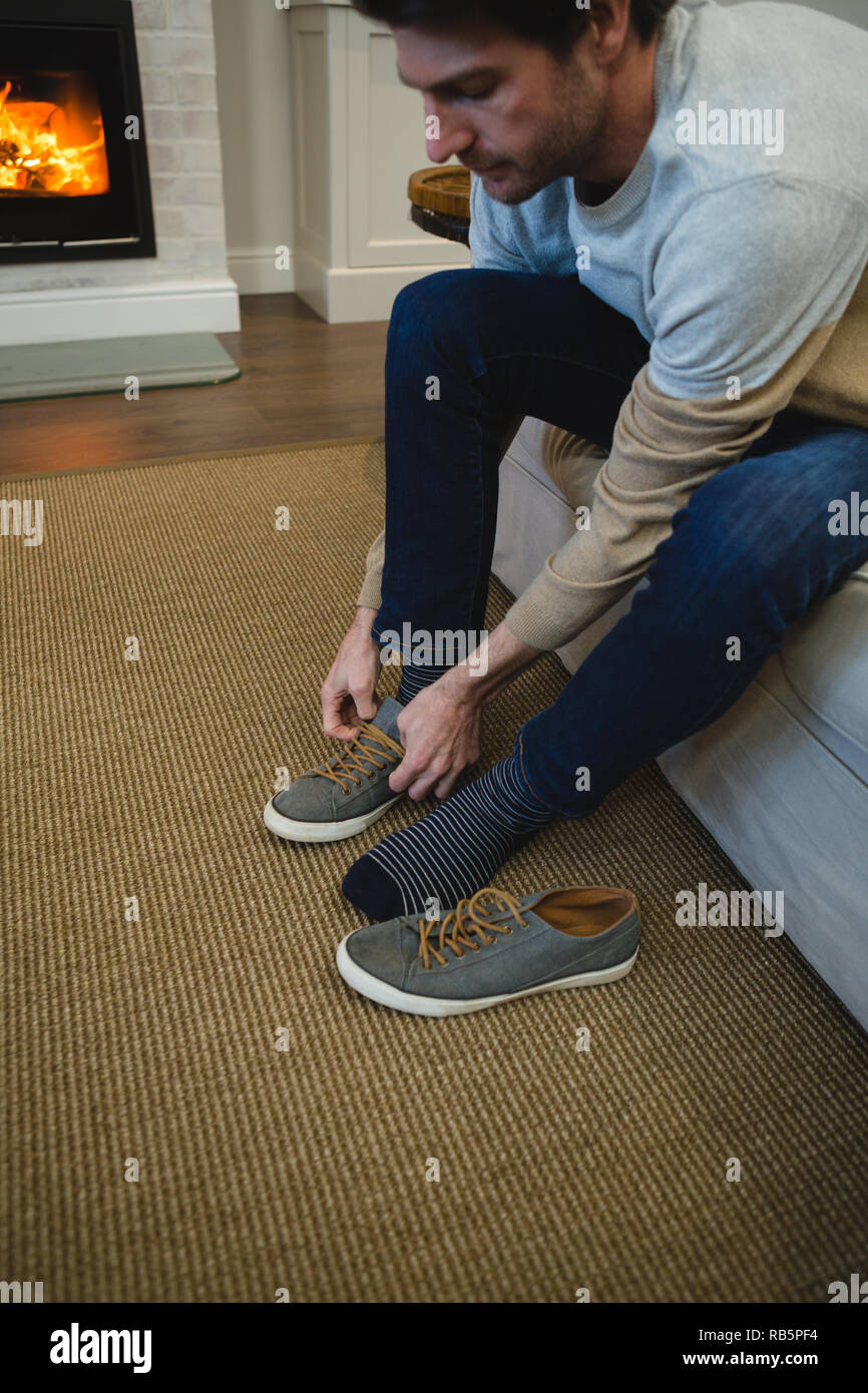 Man tying shoelaces in living room Stock Photo