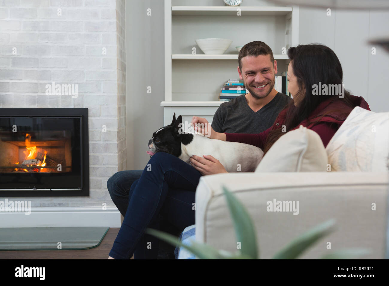 Couple relaxing with their pet dog in living room Stock Photo