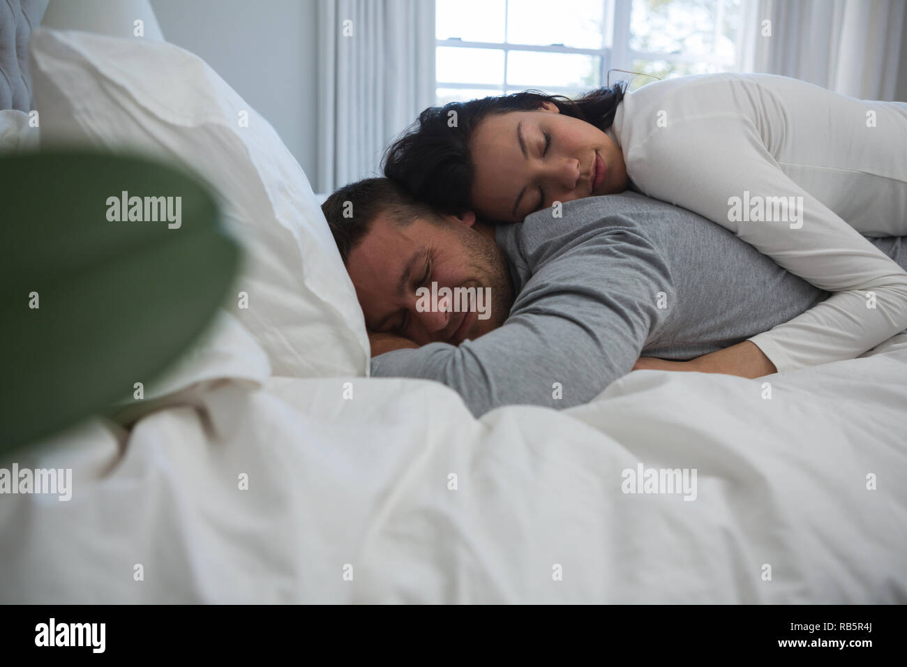 Couple sleeping on bed in bedroom Stock Photo
