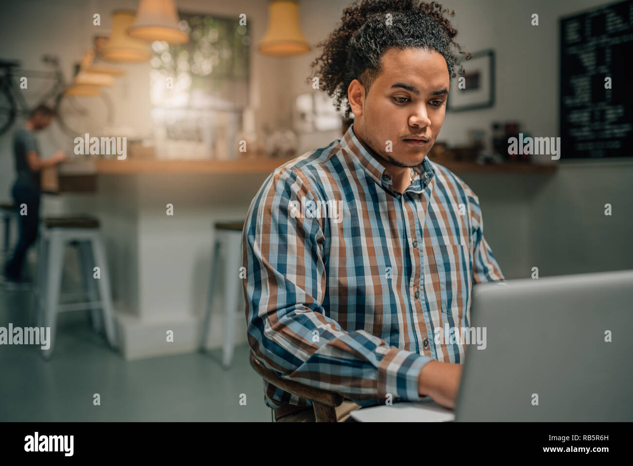 Handsome mixed race guy working on laptop in a coffee cafe Stock Photo