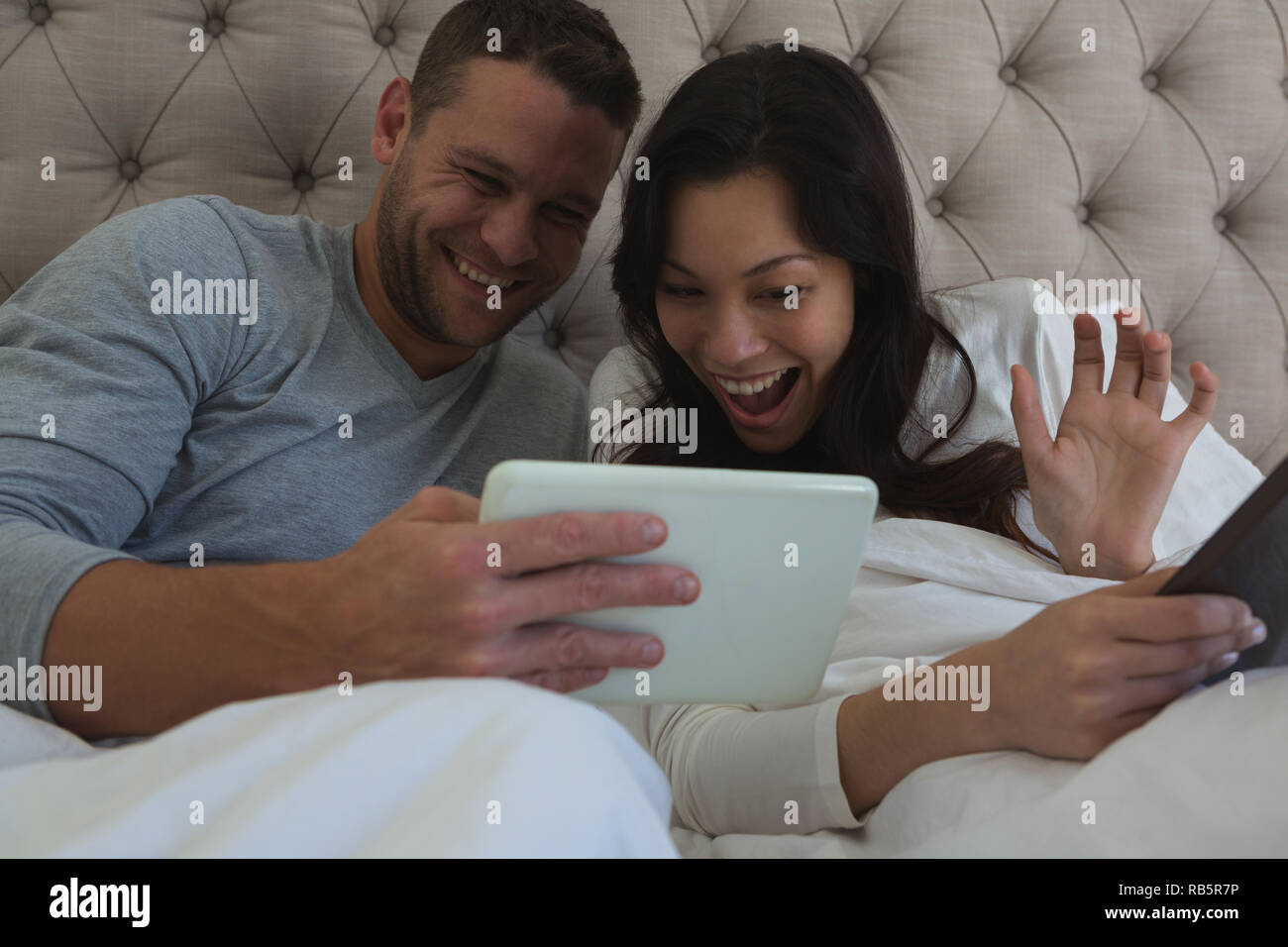 Couple using digital tablet in bedroom Stock Photo