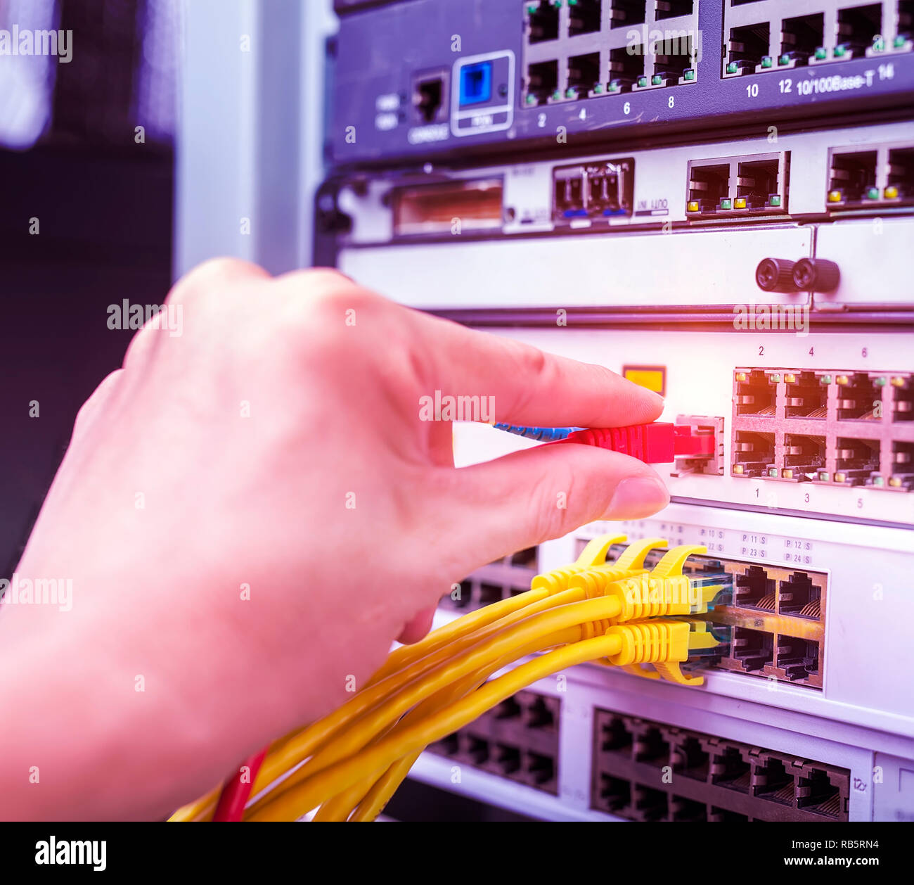 hand with network cables connected to servers in datacenter Stock Photo