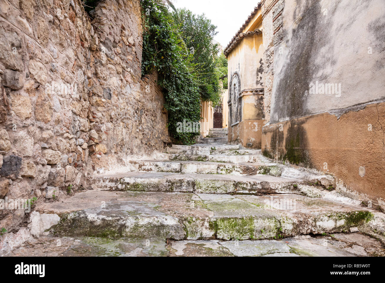 Plaka, Athens Greece. Old town narrow pedestrian streets and stairs, houses facades and stone walls. Low angle, perspective view Stock Photo
