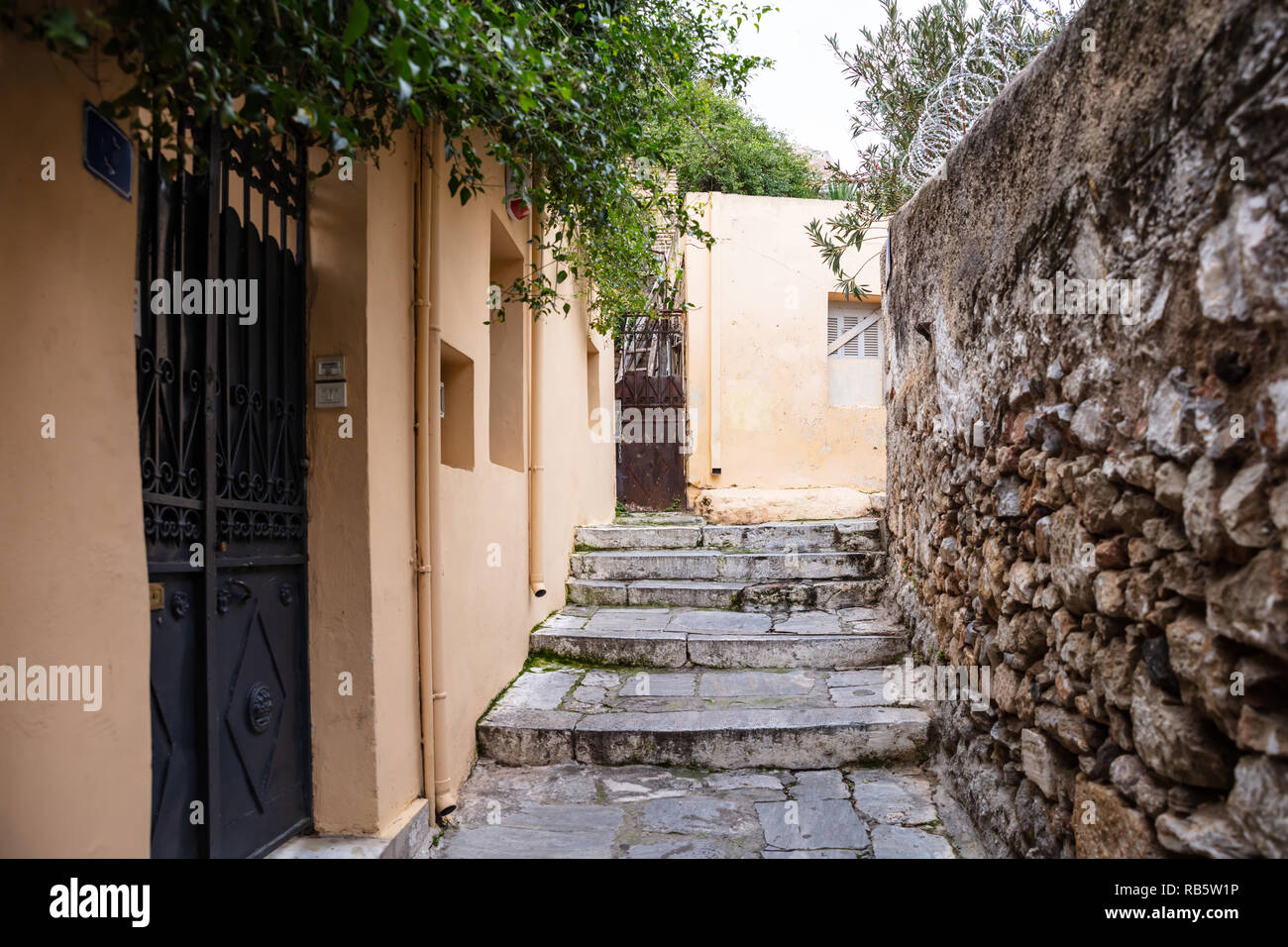 Plaka, Athens Greece. Old town narrow pedestrian streets and stairs, houses facades and stone walls. Low angle, perspective view Stock Photo