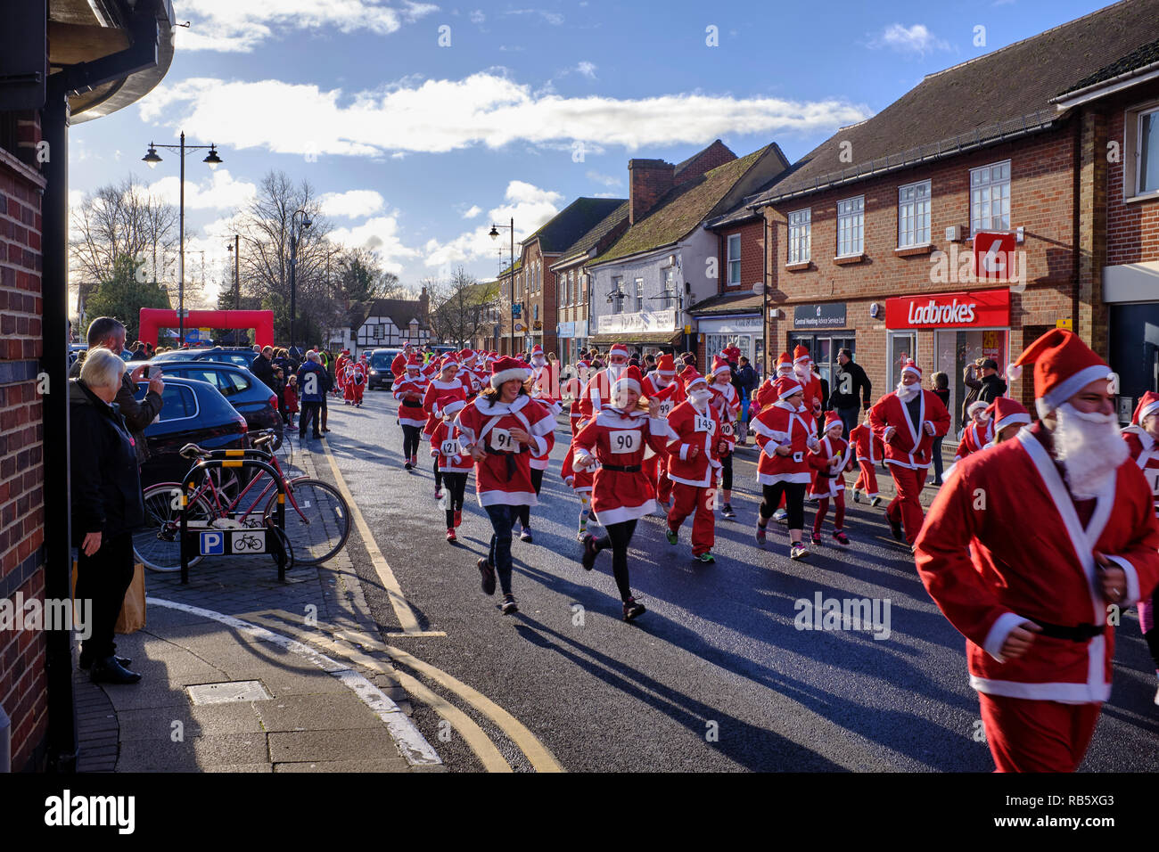 People dressed as Santa Claus who have just started taking part in the Great Thatcham Santa Fun Run in Thatcham high street while people watch on Stock Photo