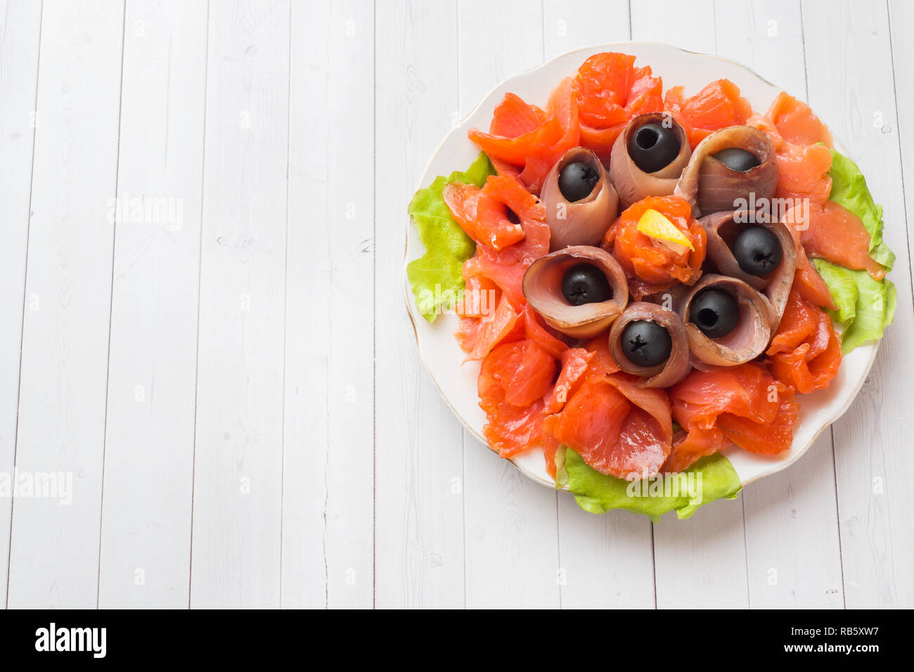 Gourmet restaurant serving a plate of smoked salt, raw white fish fillets and salmon. Delicacy fresh seafood dish with catfish, salmon meat with olive Stock Photo