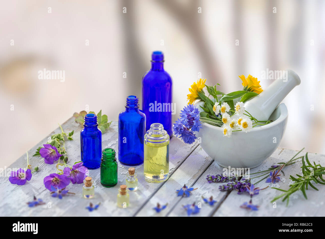 Essential oil and perfume from medicinal plant in mortar surrounded by petals Stock Photo