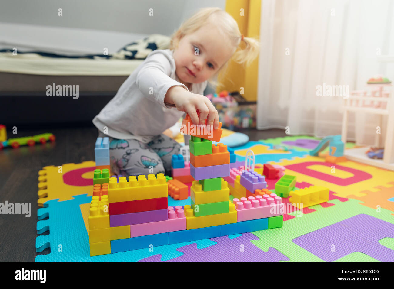 little girl playing with building blocks on the floor at home Stock Photo