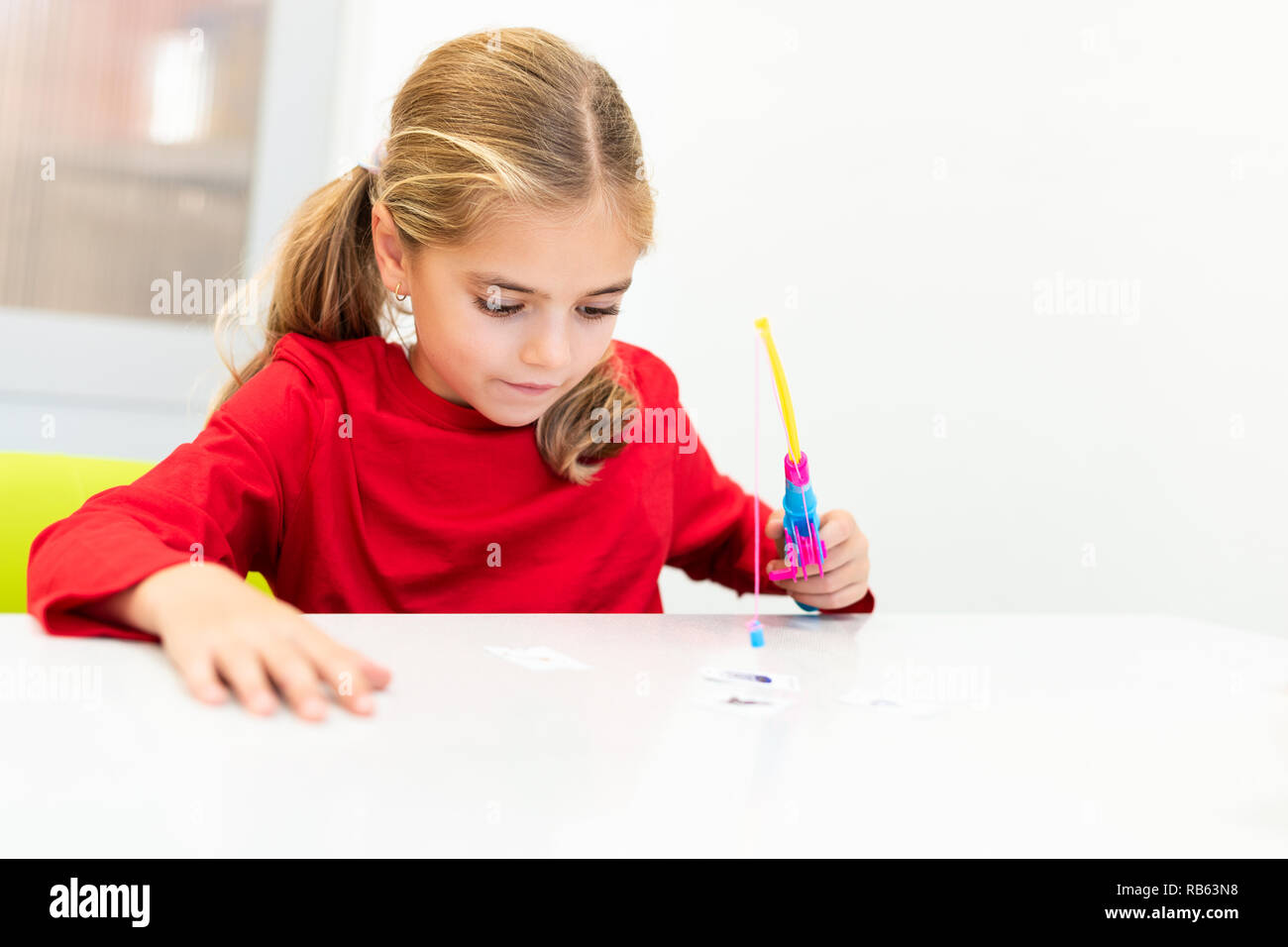 Elementary Age Girl in Child Occupational Therapy Session Doing Playful Exercises. Stock Photo