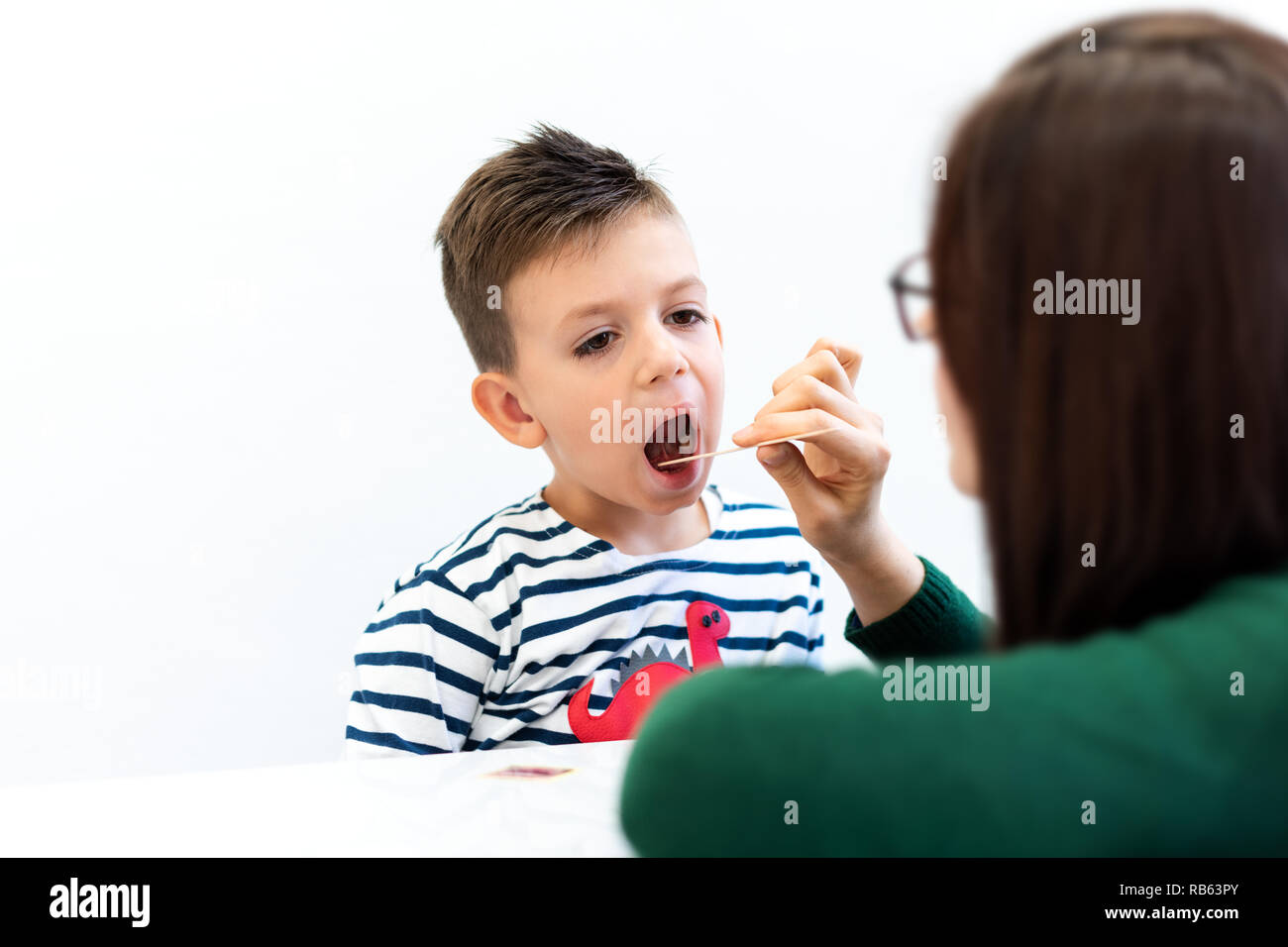 Young boy in speech therapy office. Preschooler exercising correct pronunciation with speech therapist. Stock Photo