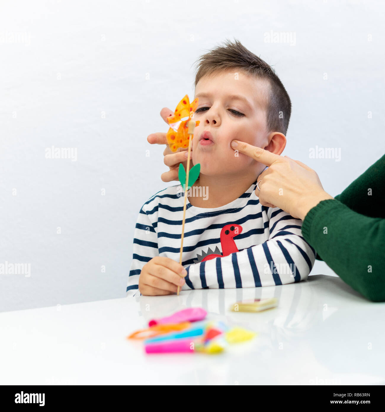 Young boy in speech therapy office. Preschooler exercising correct pronunciation with speech therapist. Stock Photo