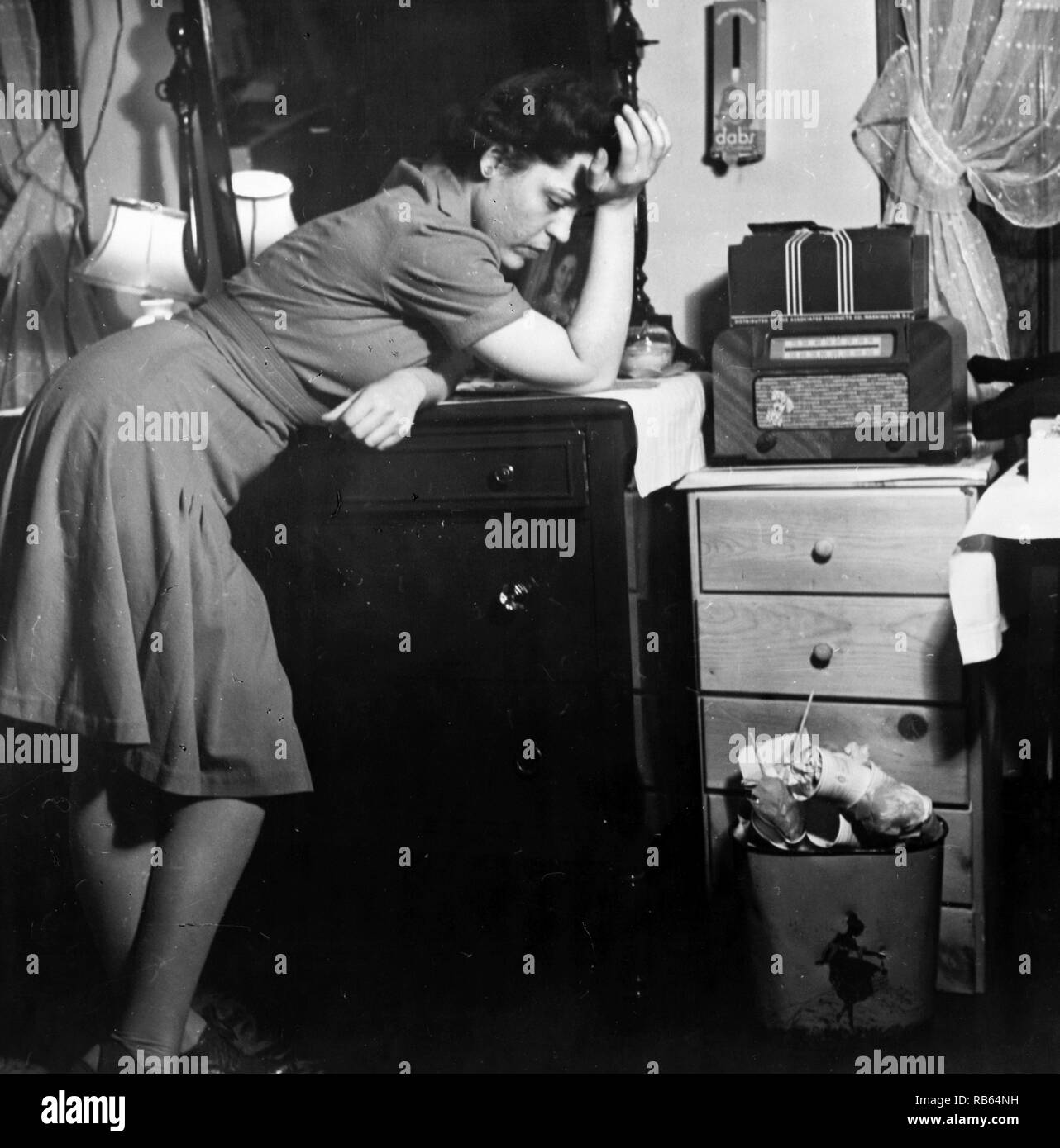 Photograph of a woman listening to a murder mystery on the radio in a boarding house. Dated 1943 Stock Photo