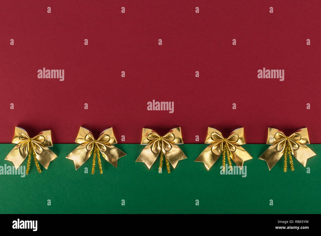 Christmas red-green background with gold bows arranged in a row Stock Photo