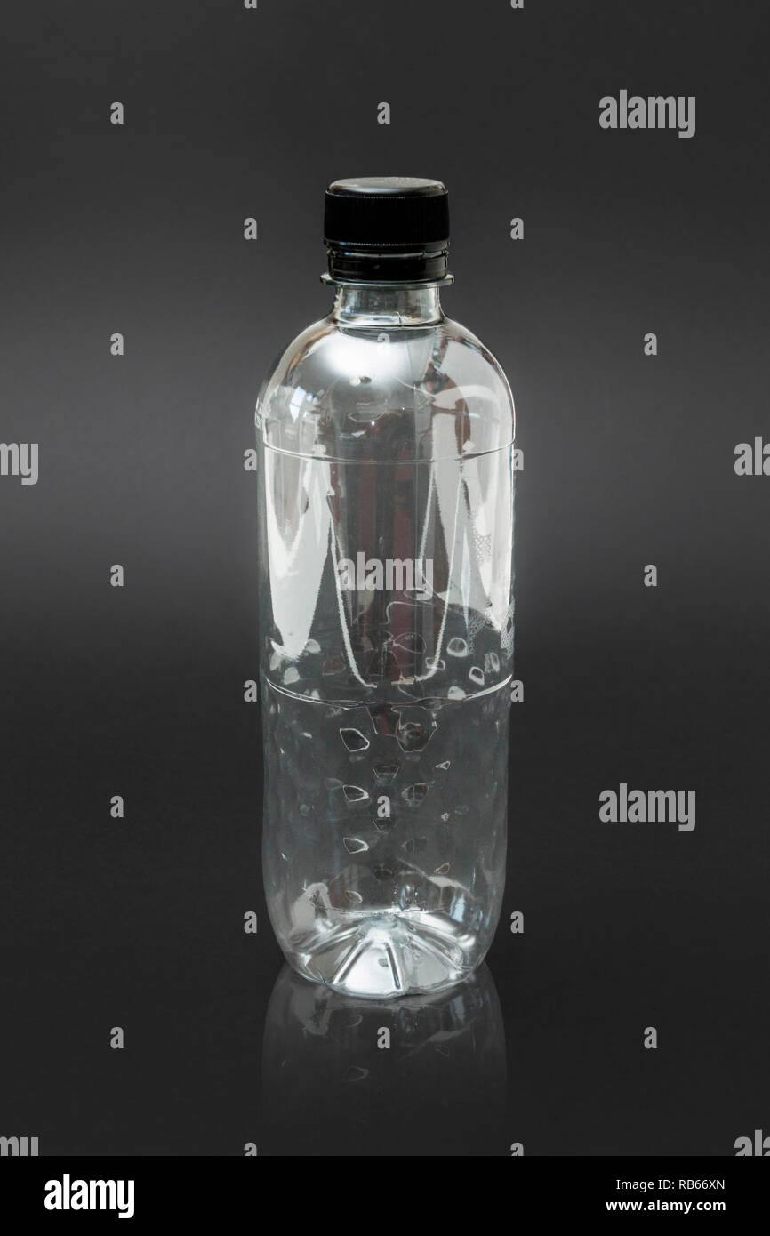 An empty generic single use plastic water bottle on a black background, no label Stock Photo