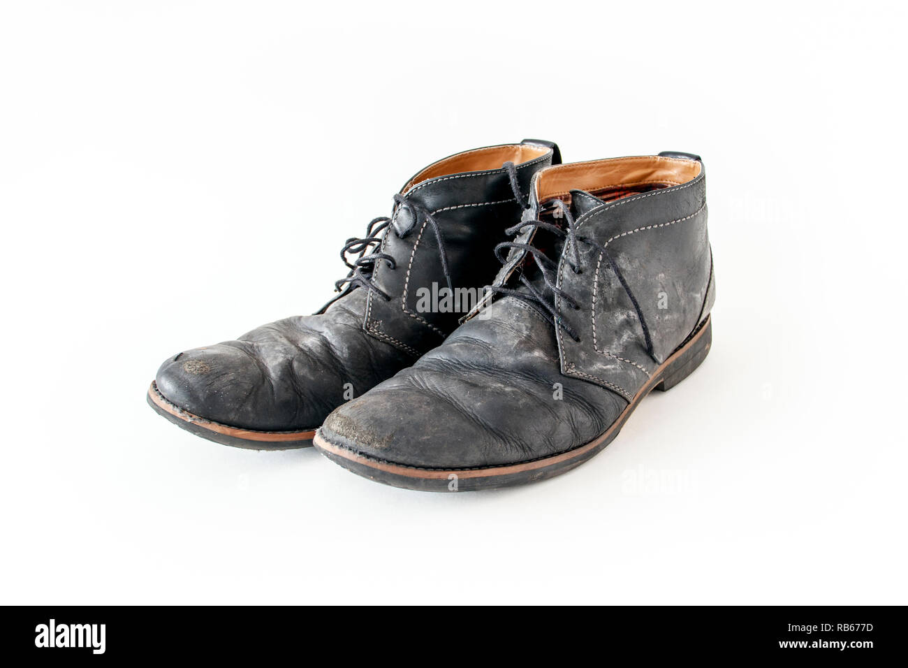 A pair of old tattered black leather lace-up shoes with water stains Stock Photo