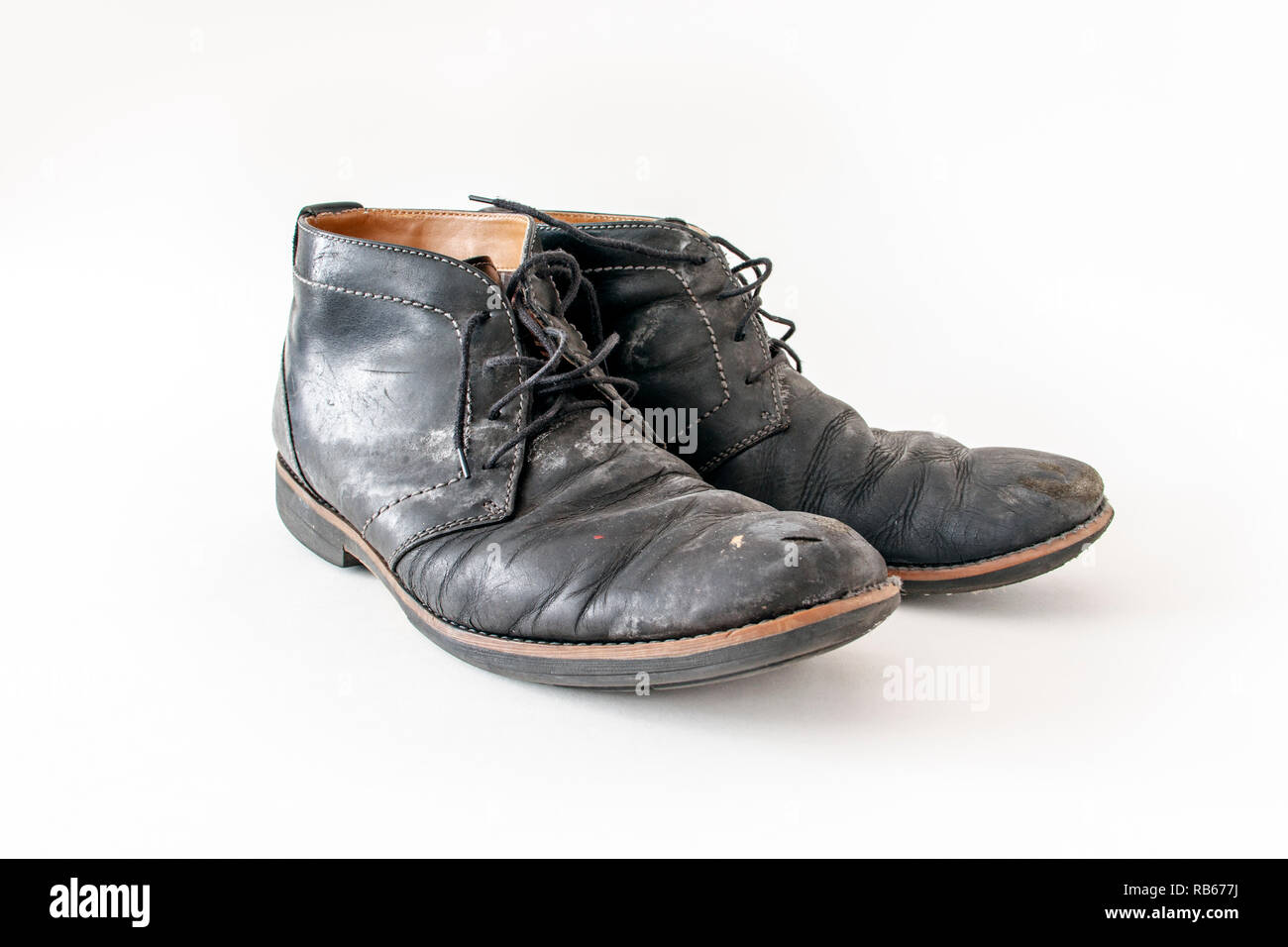 A pair of old tattered black leather lace-up shoes with water stains Stock Photo