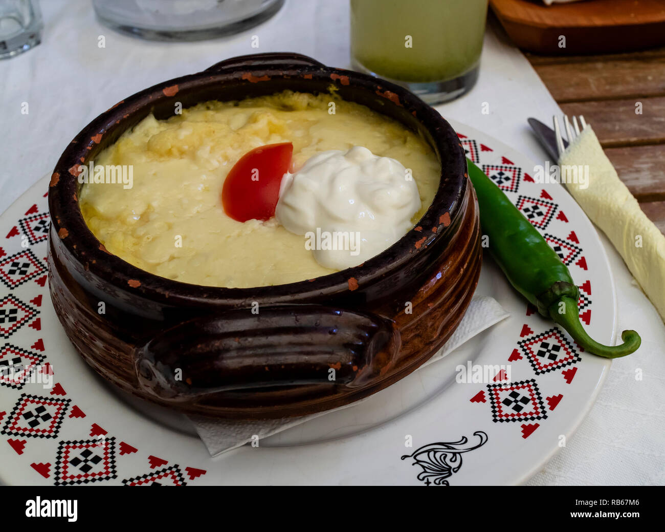 Mamaliga, a romanian traditional dish made of polenta, served with sour cream and a slice of tomato Stock Photo