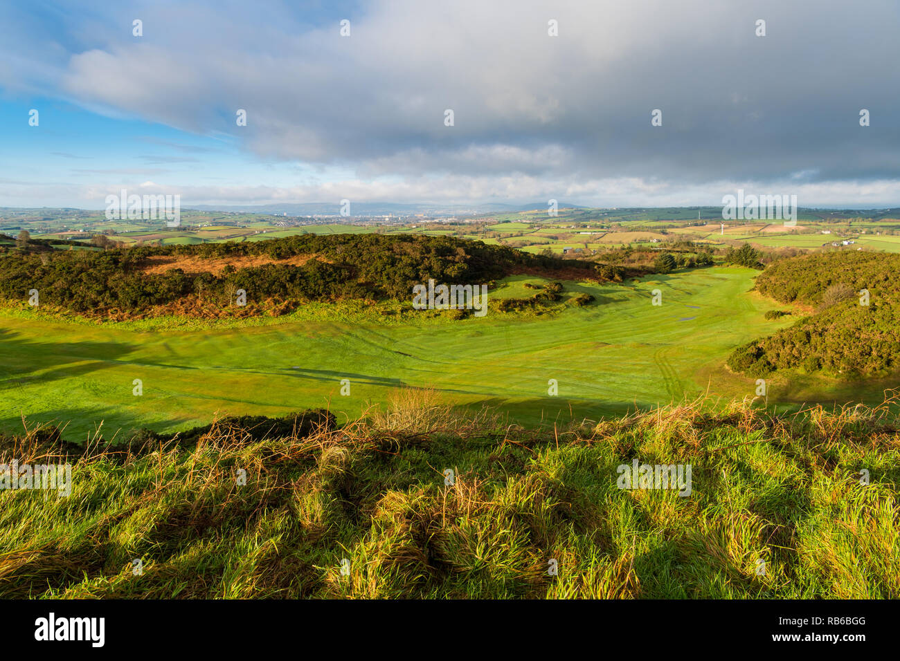Eary morning golden hour light reveals a lush green golf course with a landscape of grass and fields in County Down, Northern Ireland Stock Photo