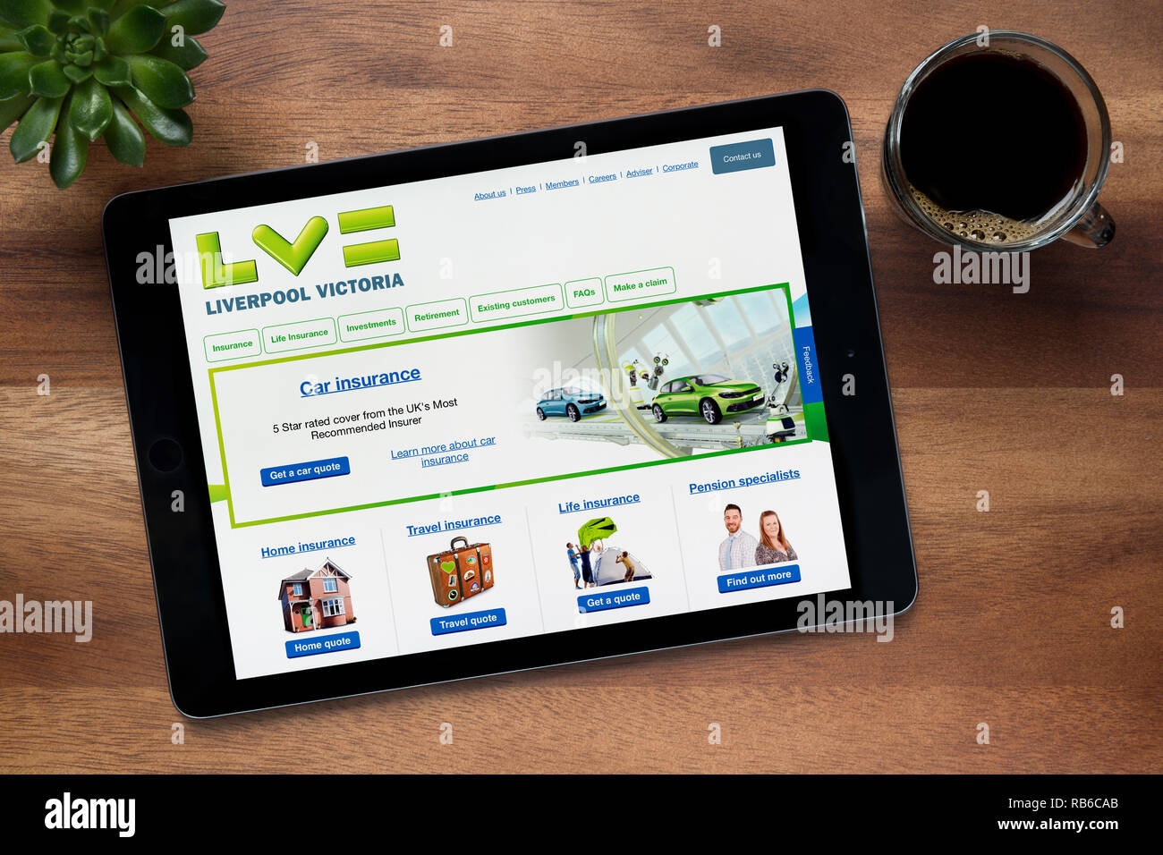 The website of Liverpool Victoria is seen on an iPad tablet, on a wooden table along with an espresso coffee and a house plant (Editorial use only). Stock Photo