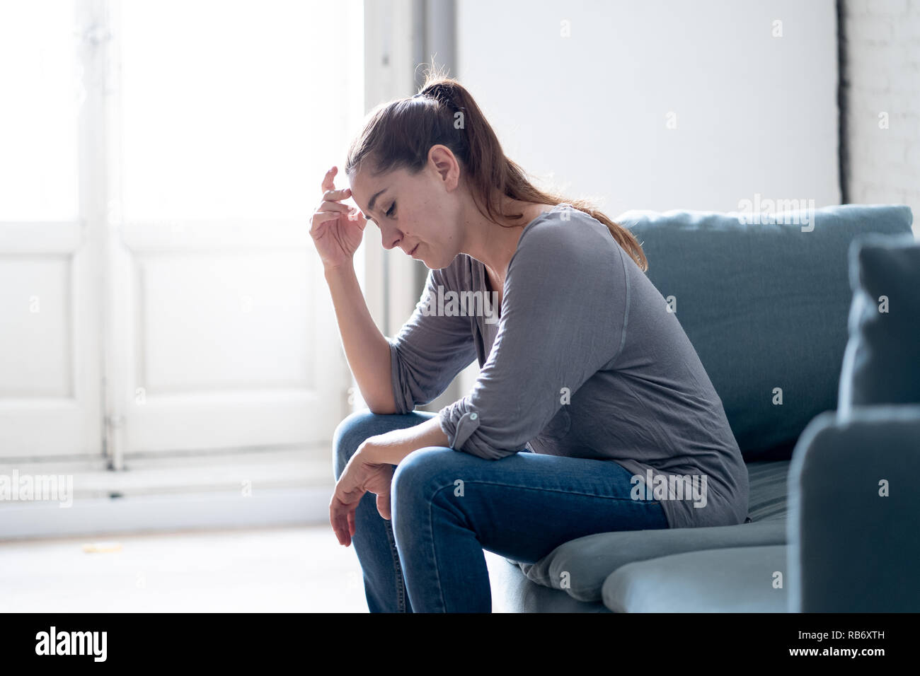 Young attractive latin woman lying at home living room couch feeling sad tired and worried suffering Depression in Mental health, Problems Emotional p Stock Photo