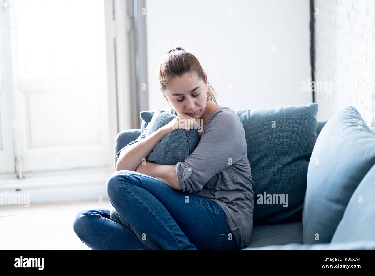 Young attractive latin woman lying at home living room couch feeling sad tired and worried suffering Depression in Mental health, Problems Emotional p Stock Photo