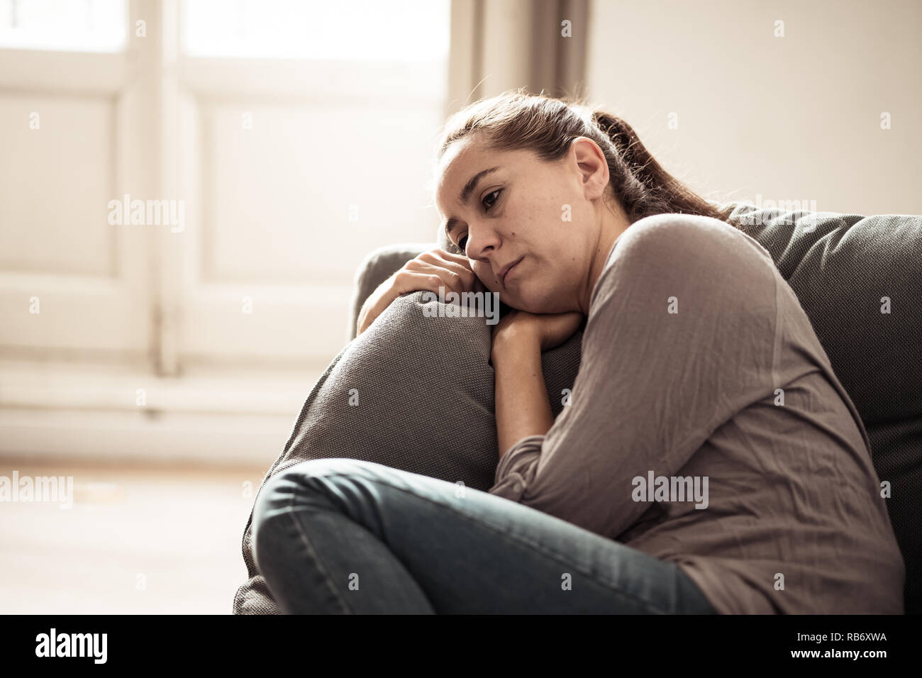 Young attractive latin woman lying at home living room couch feeling sad tired and worried suffering Depression in Mental health, Problems Emotional p Stock Photo