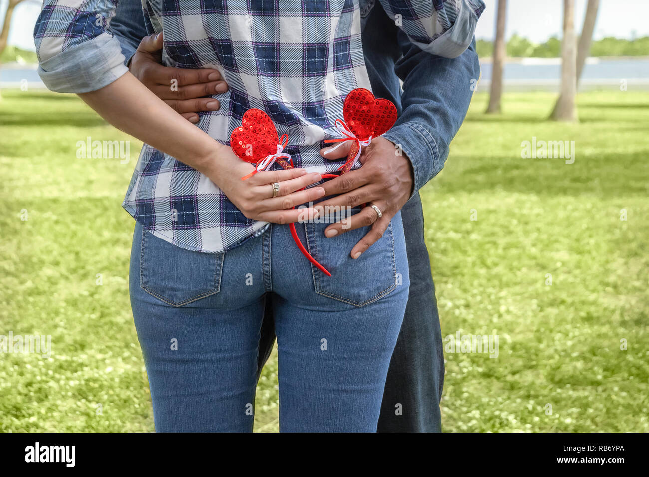 The husband and wife grab the Valentine headband decoration at the same time from her back pocket. Stock Photo