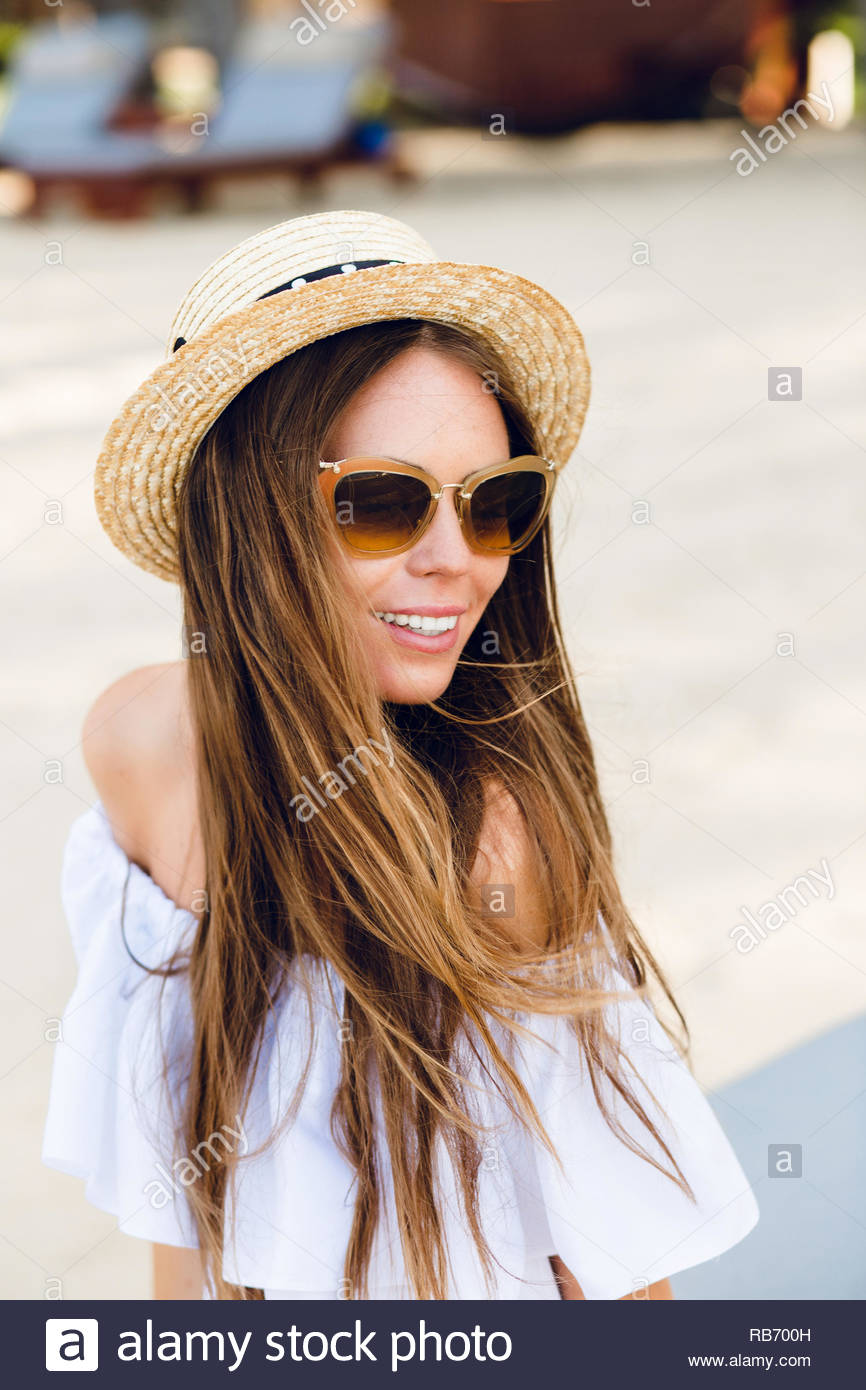 Cute Girl In Brown Sunglasses And Straw Hat Smiles Charmingly She