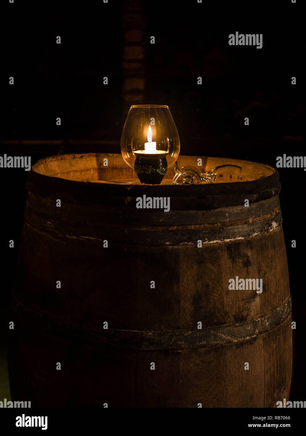 Small candlelight in a glass in a almost forgotten wine cellar Stock Photo