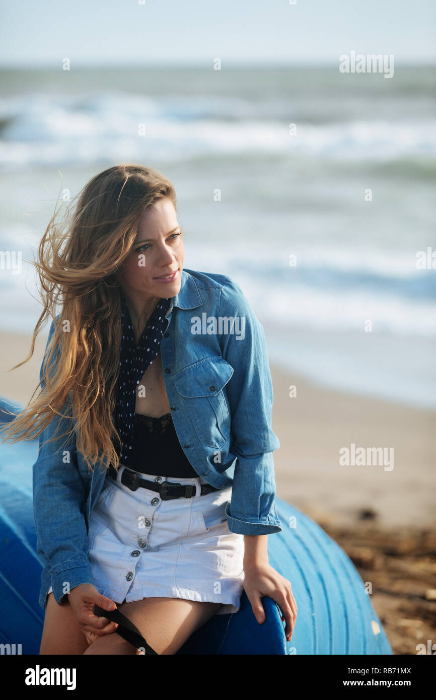 happy young woman sitting and posing on the blue boat in front of ...