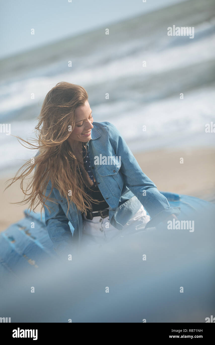 happy young woman sitting and posing on the blue boat in front of ...