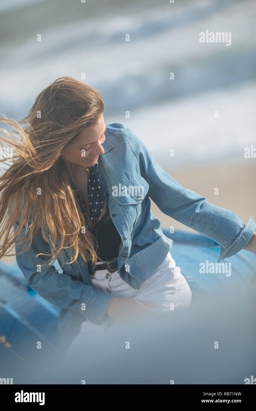 happy young woman sitting and posing on the blue boat in front of ...