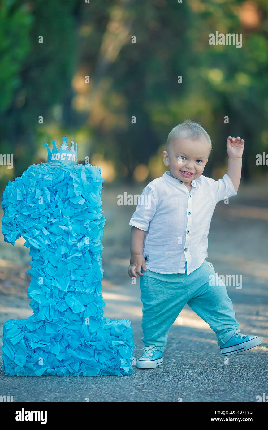 little baby boy sitting close to number one birthday number blue color