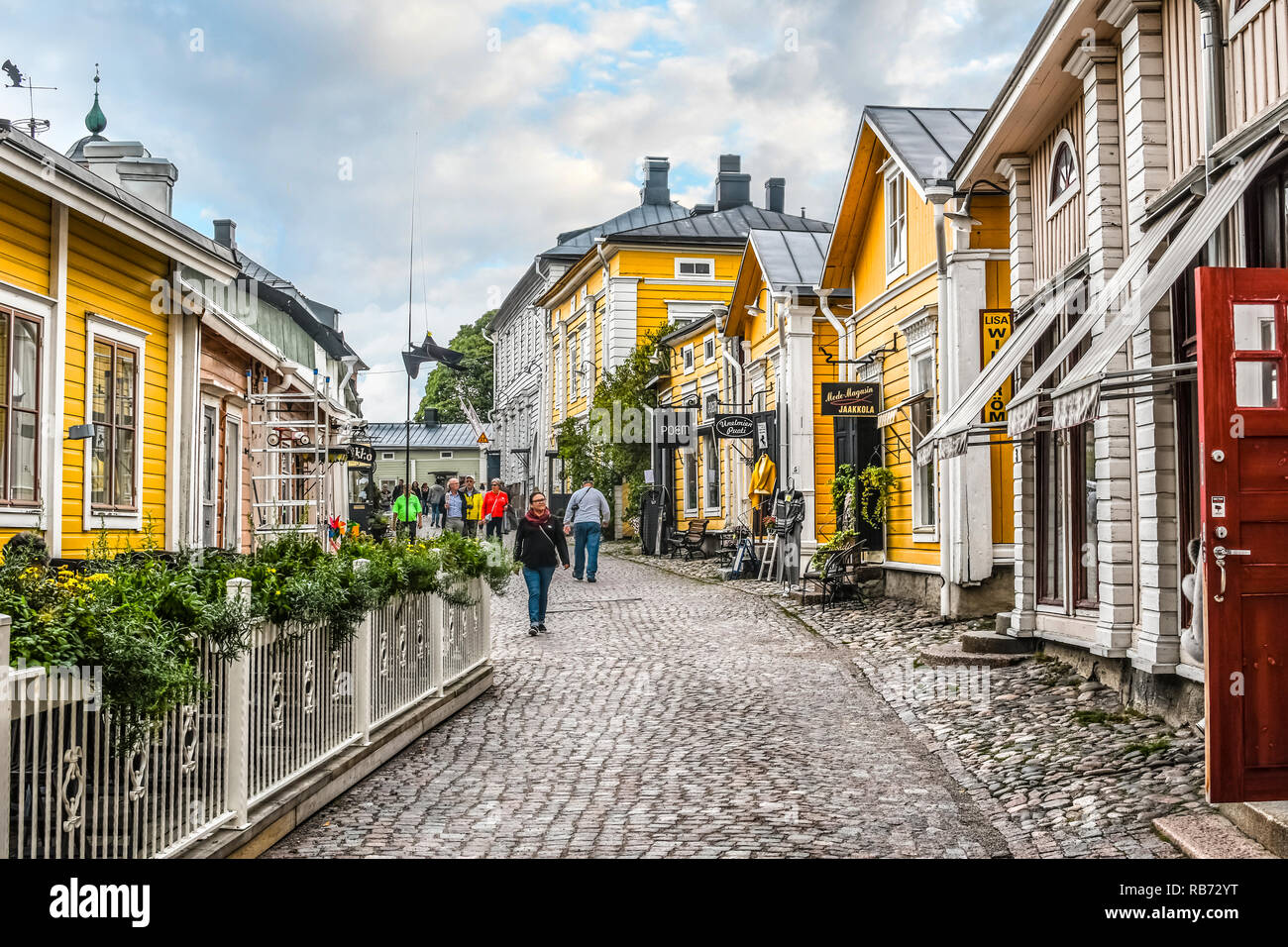 Tourists and local Finns walk past shops along the cobbled streets of the medieval old town section of Porvoo, Finland. Stock Photo
