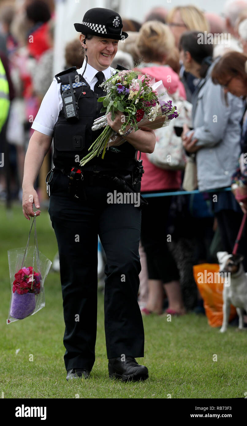 A Police Officer carries flowers and gifts as The Prince of Wales and The Duchess of Cornwall attend The Sandringham Flower Show held on the royal est Stock Photo