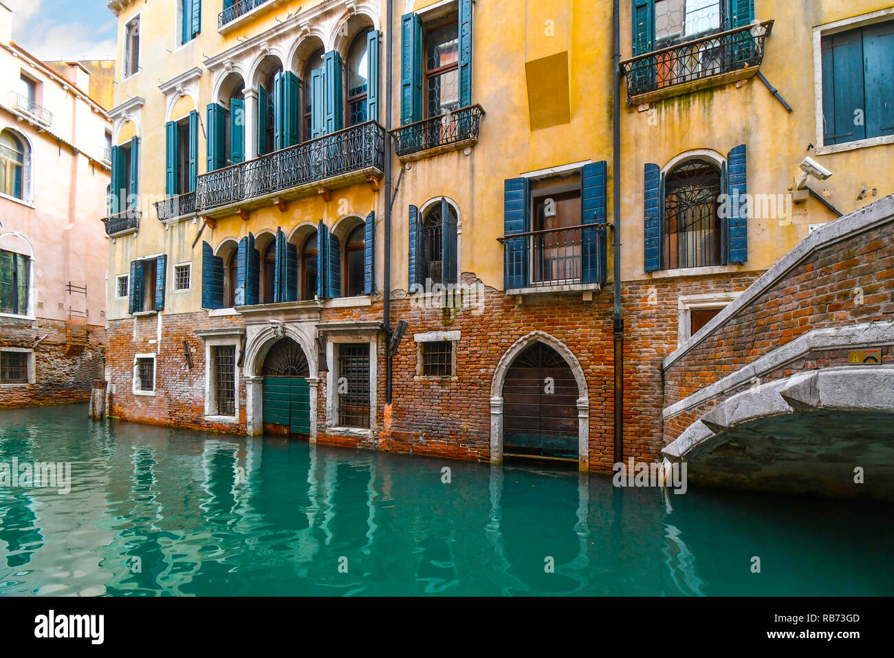 A typical, picturesque and colorful residential canal in the historic center of Venice, Italy with emerald green water. Stock Photo