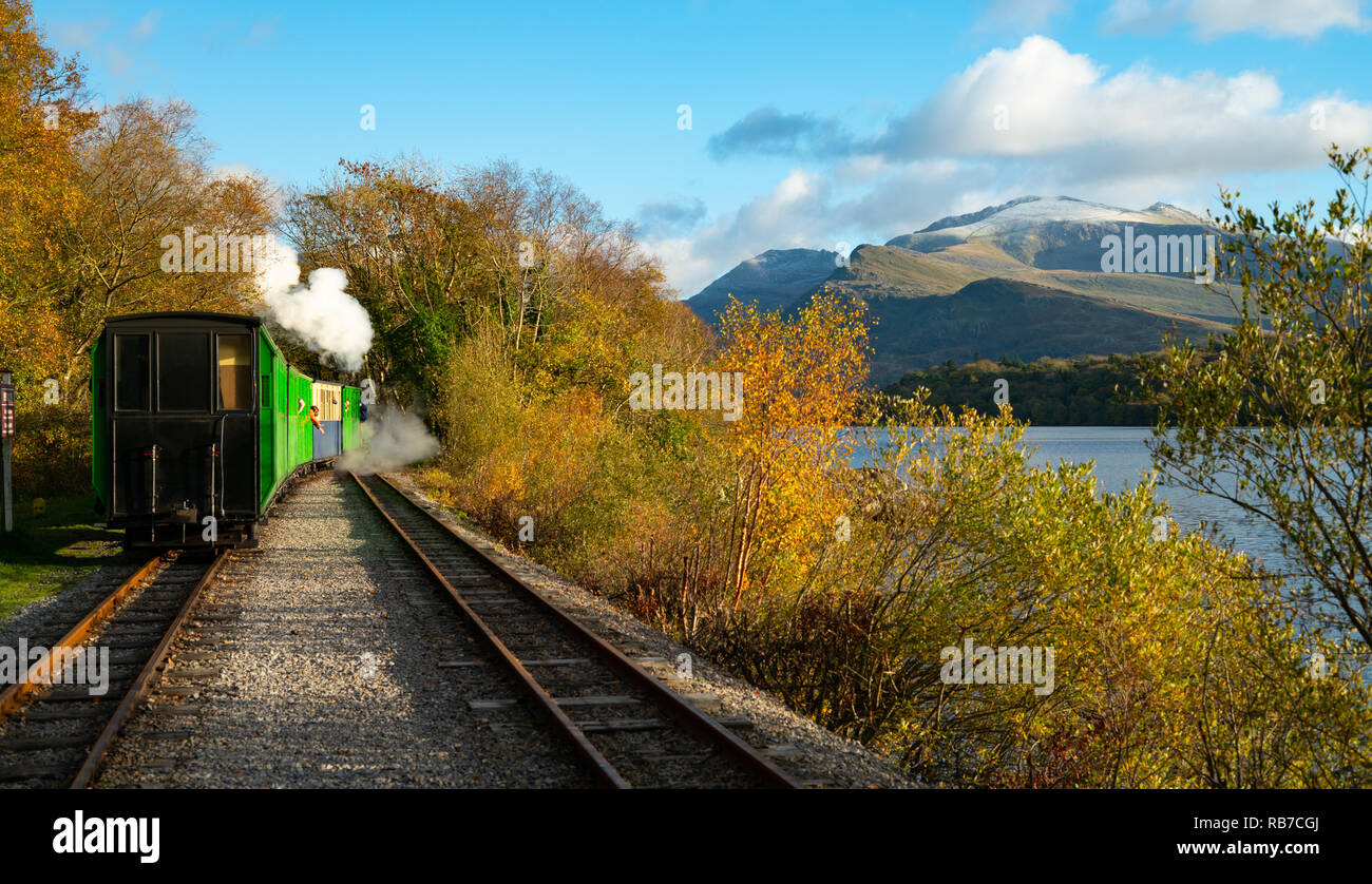 Llanberis Lake Railway, along side Padarn Lake, with early snow on Mount Snowdon. Image taken in October 2018. Stock Photo