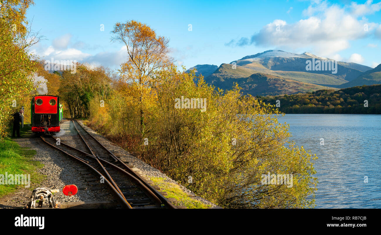 Llanberis Lake Railway, along side Padarn Lake, with early snow on Mount Snowdon. Image taken in October 2018. Stock Photo