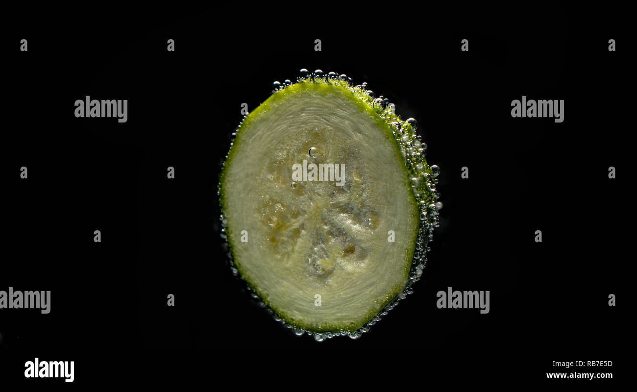 Zucchini slice with bubbles of carbonated water isolated on black