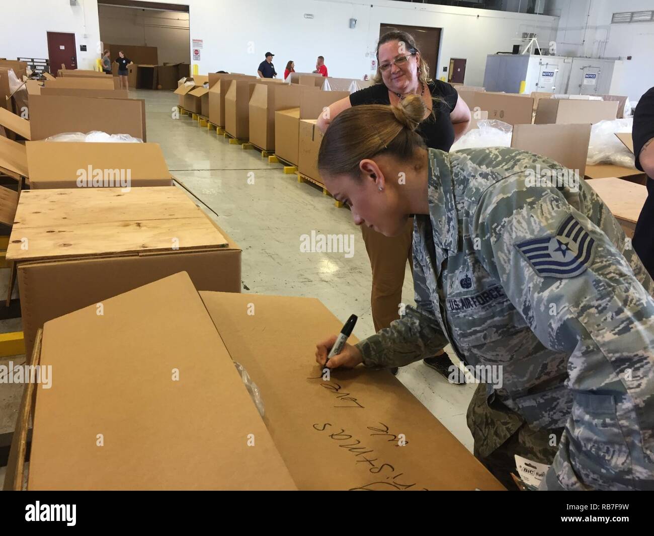 ANDERSEN AIR FORCE BASE, Guam -- U.S. Air Force Tech. Sgt. Sharry Barnshaw, assigned to the 436th Communications Squadron, Dover AFB, DE, writes a message on the care package she assembled during pack day for Operation Christmas Drop (OCD) 2016, Dec. 3, 2016. Roughly 200 volunteers packed 140 boxes with more than 40,000 lbs. of critical supplies gathered through donations. OCD is a U.S. Air Force tradition that started in 1952, delivering needed essentials to approximately 20,000 people living in more than 50 isolated islands throughout the Commonwealth of the Northern Marianas Islands, Federa Stock Photo
