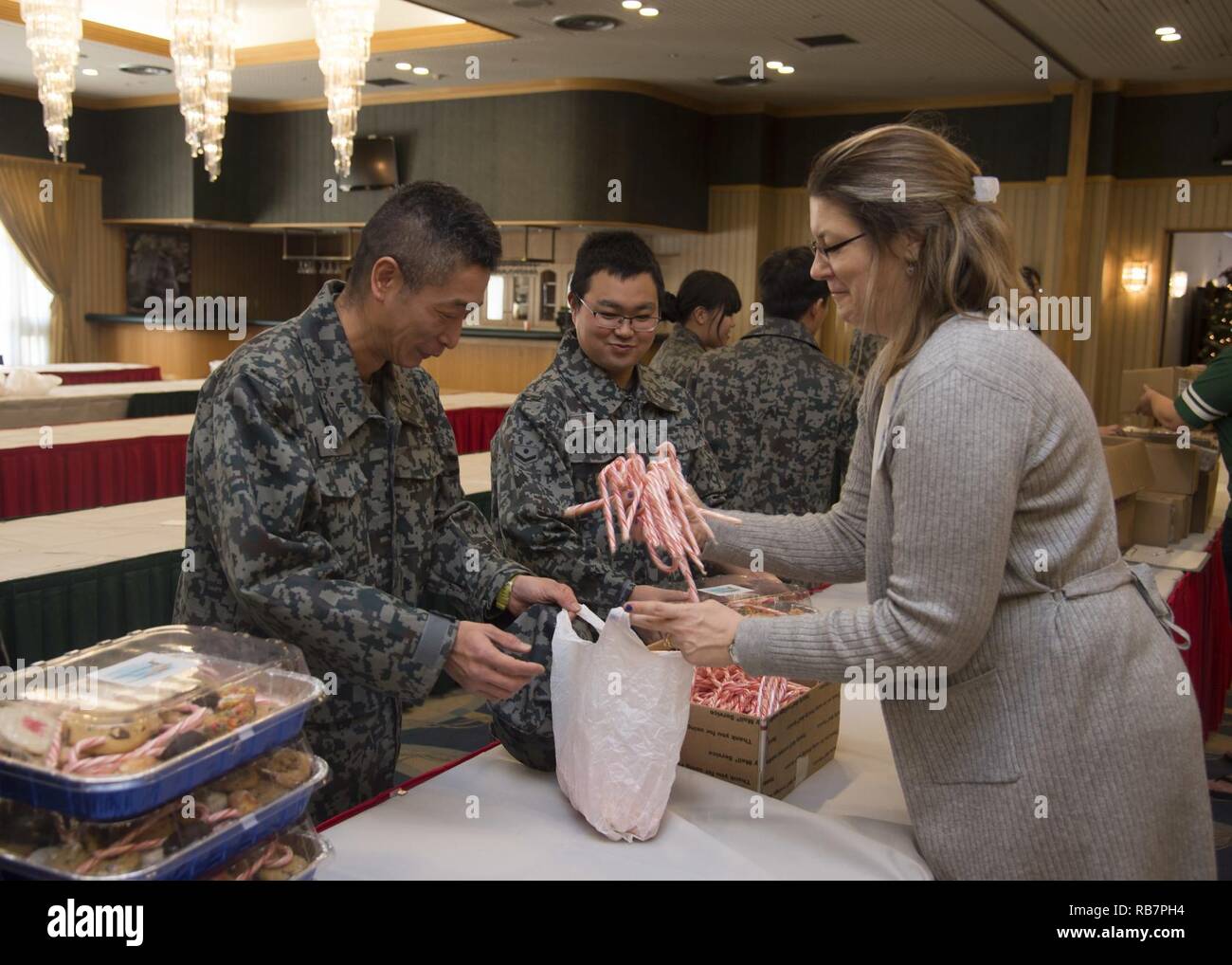 Japan Air-Self Defense Force members receive candy canes from Karri Frizzell, the Cookie Caper committee leader, during the annual event at Misawa Air Base, Japan, Dec. 7, 2016. The Cookie Caper leads also included JASDF members because they are also away from their families during the holidays. Additionally, the volunteers provided a CD of holiday music as an extra gift to the JASDF members. Stock Photo