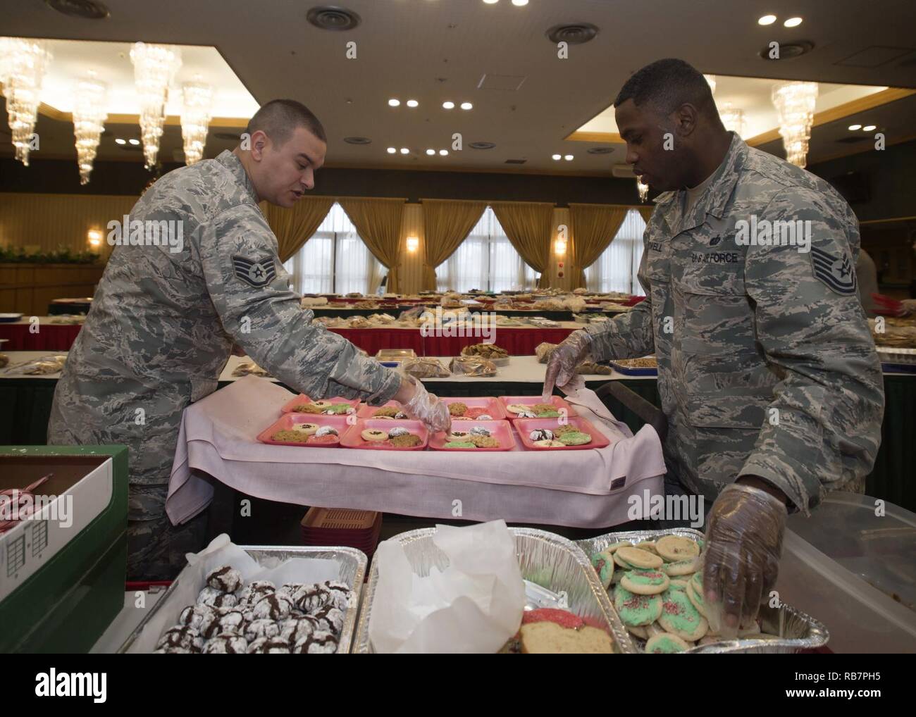 U.S. Air Force Staff Sgt. Robert Smalling, left, the 35th Medial Operations Squadron immunizations NCO in charge, and Tech. Sgt. Johnnie Powell, right, the 35th Force Support Squadron readiness and mortuary affairs NCO in charge, divide cookies during the annual Cookie Caper event at Misawa Air Base, Japan, Dec. 7, 2016. Volunteers gave more than 14,400 home-baked cookies to the event, while others donated dough to be cooked. Stock Photo