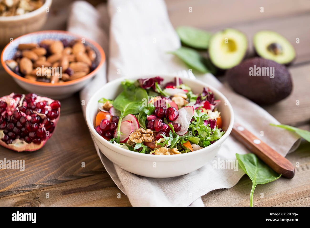 Fresh healthy and oragnaic salad with spinach, arugula leaves, radish, tomatoes, organic nuts and pomegranate seeds. Vegan salad diet concept Stock Photo