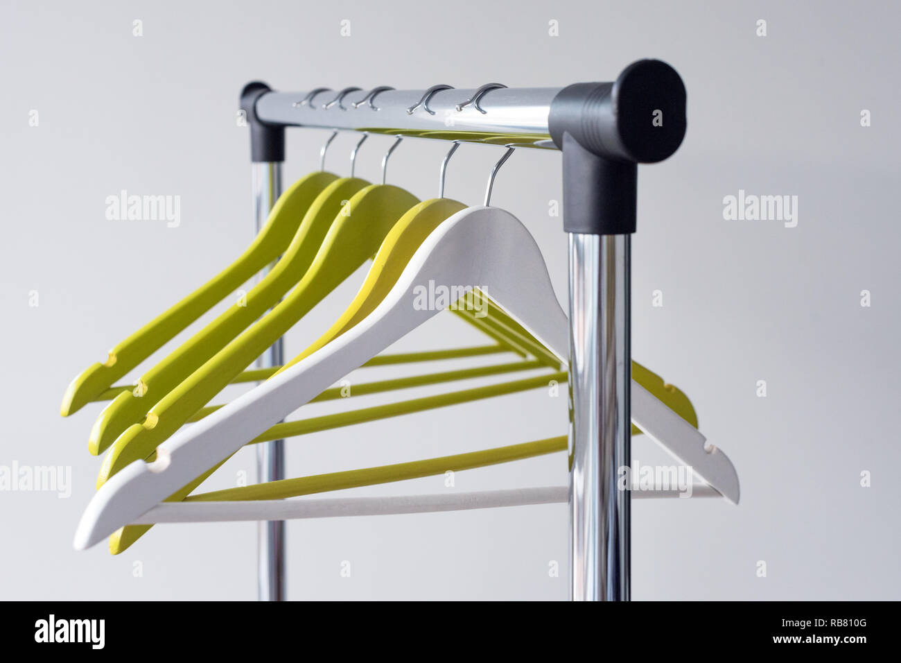 Empty clothes hangers on metal rail against grey background. Rectangular  metal clothing rail with empty color wooden coat hangers Stock Photo - Alamy