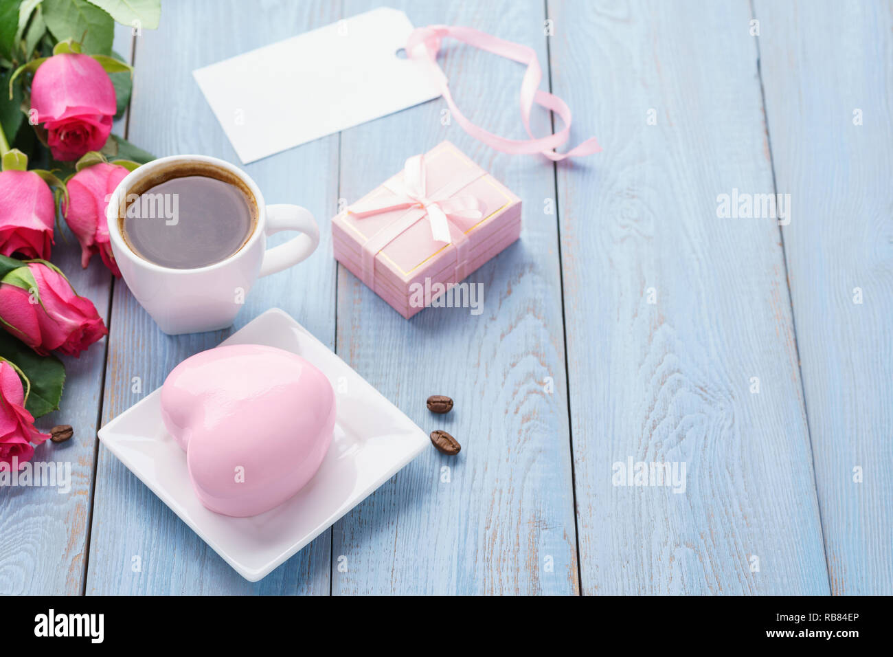Valentine's Day greeting card or sale mockup with pink roses, gift box, heart shaped mousse cake and cookies. Stock Photo