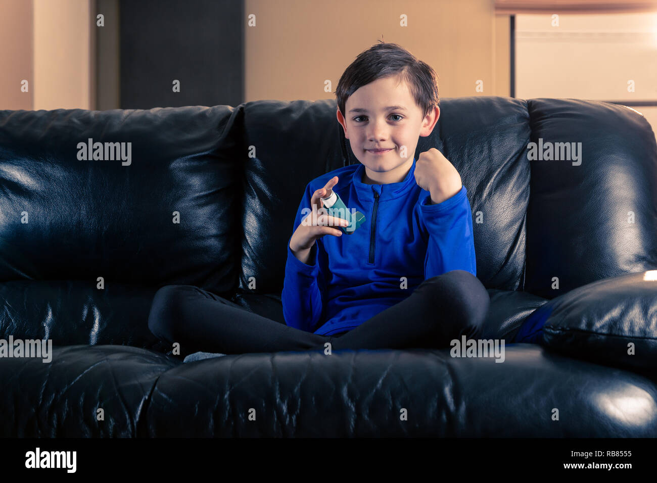 8 year old boy wearing sportive clothing with asthma inhaler sitting in
