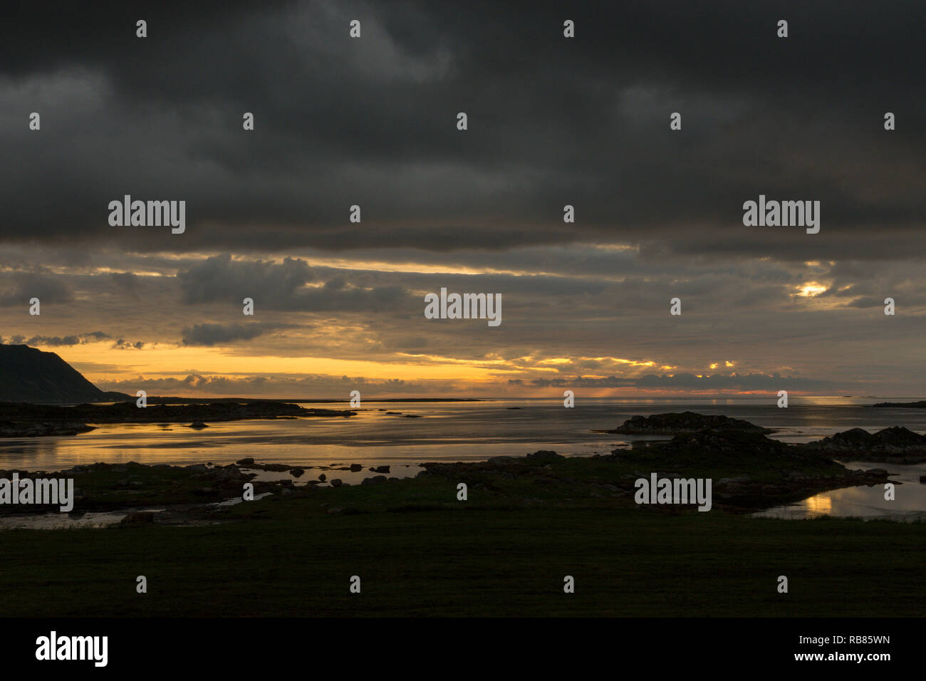 Sunset and midnight sun by the sea and mountains near Gimsøya on the Lofoten islands in Norway